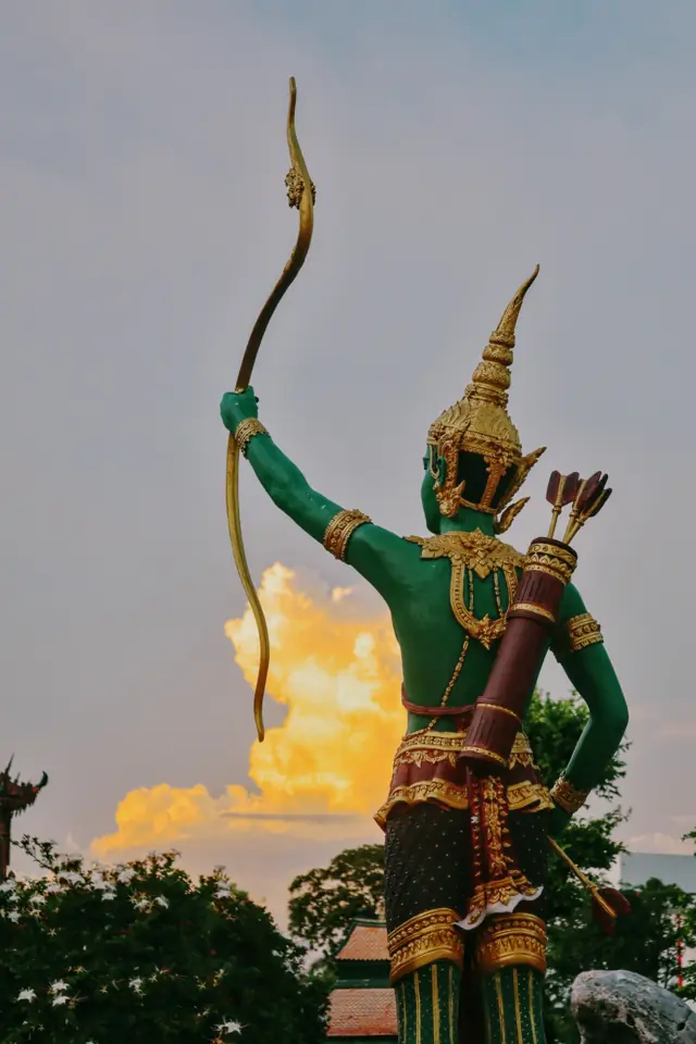 A green and gold archer statue at sunset