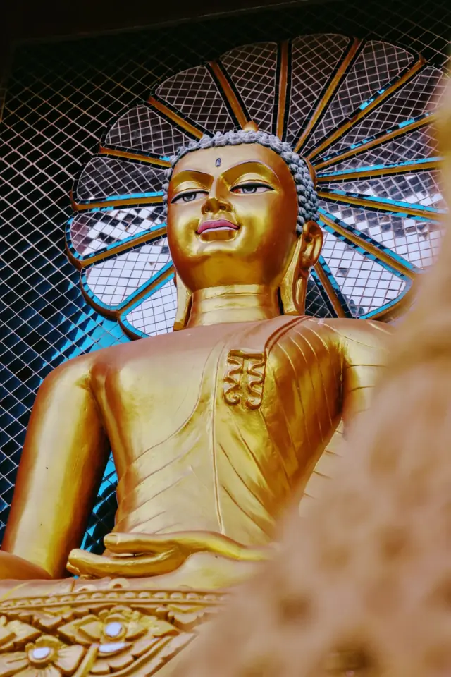 A gold Buddha in front of a mirrored halo