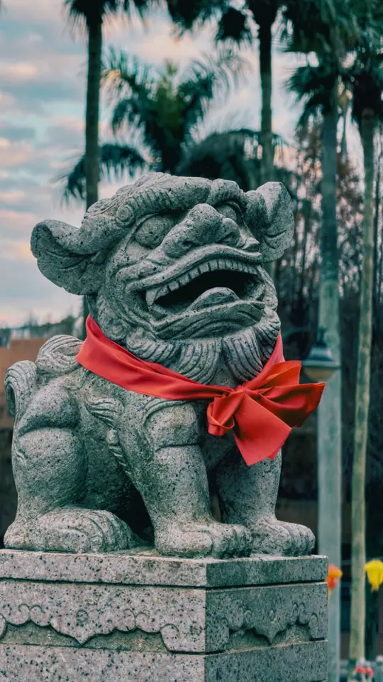 A stone guardian lion wearing a red ribbon