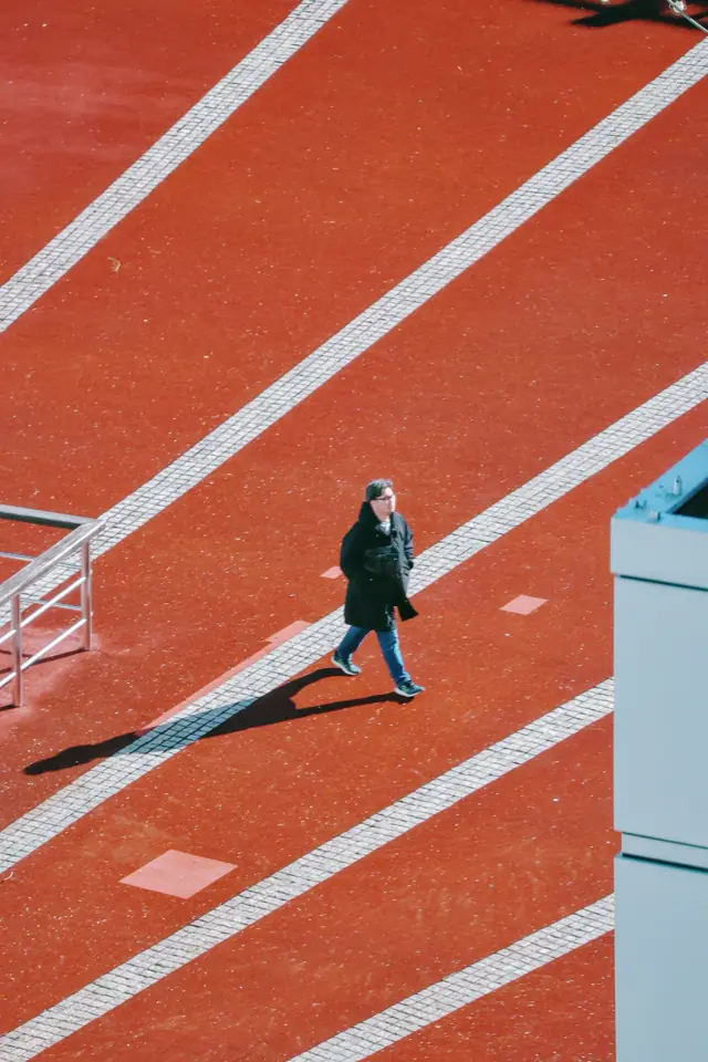 A lone walker on a red running track