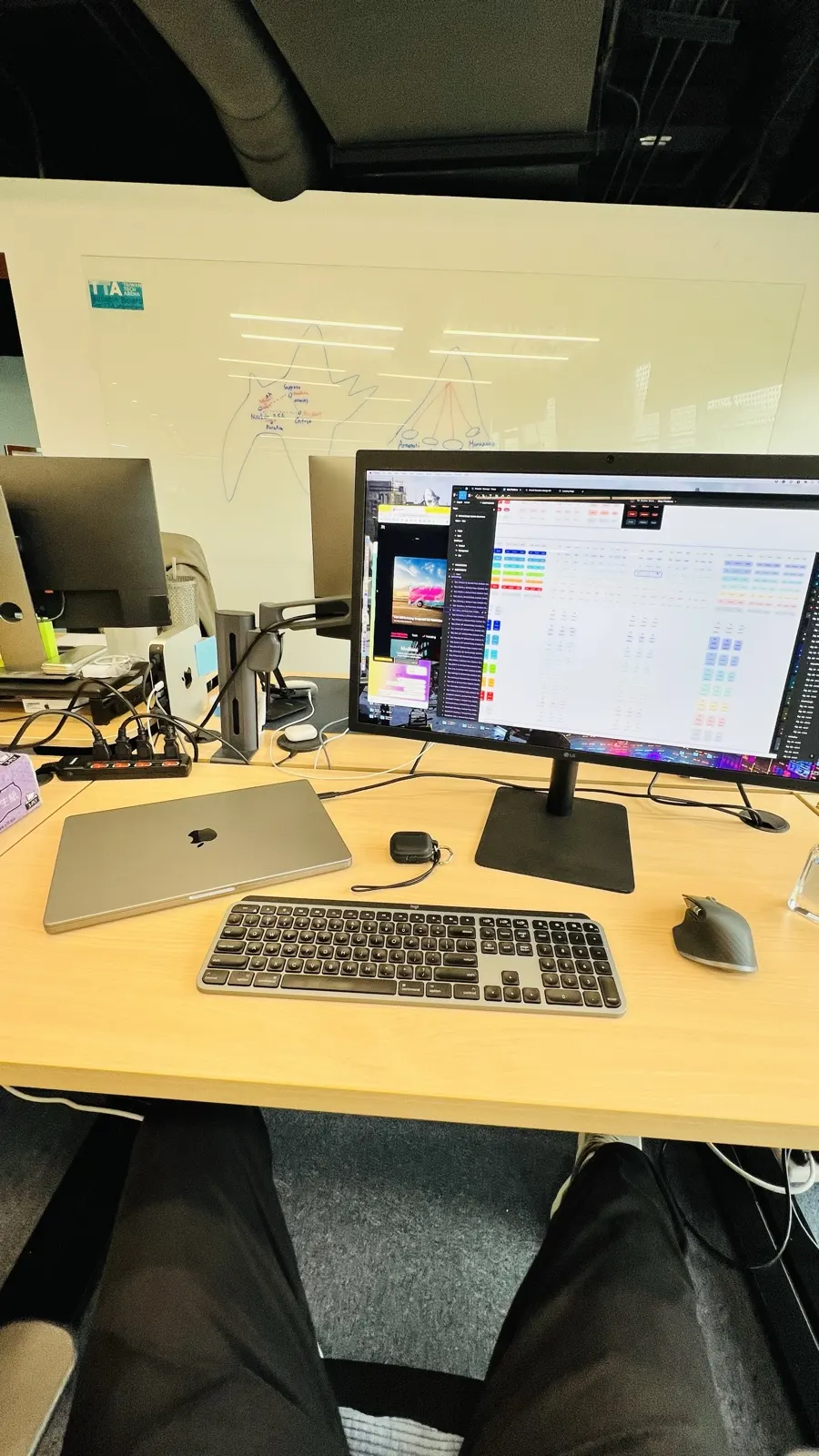 A desk with a monitor open on design files, a laptop, keyboard and mouse